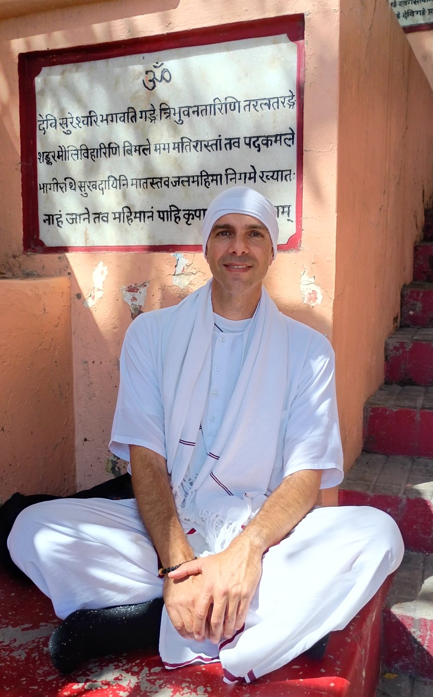 Sahaja Bodha seated at Shivananda Ghat beneath a Sanskrit inscription